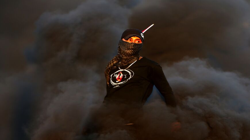 A Palestinian demonstrator stands amidst smoke from burning tires during a protest against the tension in Jerusalem and the Israeli-Gaza fighting, on May 17, 2021, in the occupied West Bank, near the settlement of Beit El next to Ramallah.