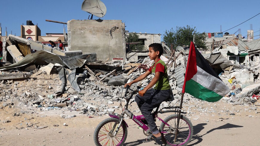 A Palestinian child rides his bicycle in front of the ruins of a building destroyed during recent Israeli bombing in Rafah, in the southern Gaza Strip, on May 26, 2021.