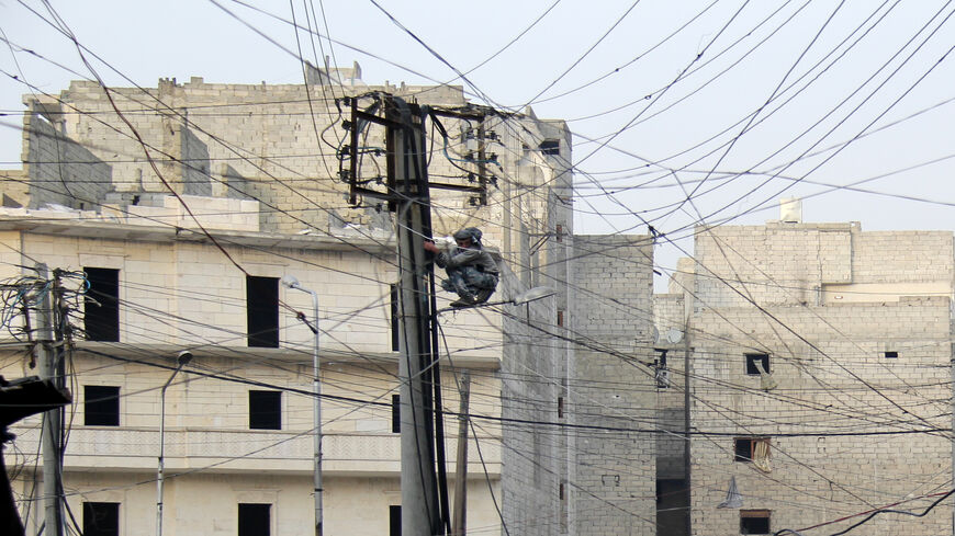 A man tries to fix electrical wires in the Salahuddin neighborhood, Aleppo, Syria, Jan. 27, 2014.