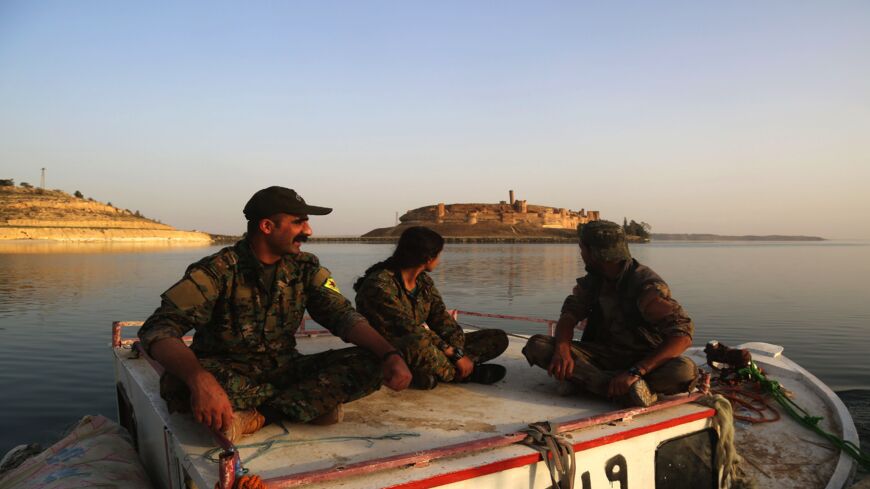 Members of the US-backed Syrian Democratic Forces (SDF), made up of an alliance of Arab and Kurdish fighters, look toward the Jaabar Castle as they sit on a boat at Lake Assad, an enormous reservoir created by the Tabqa dam, on April 29, 2017.