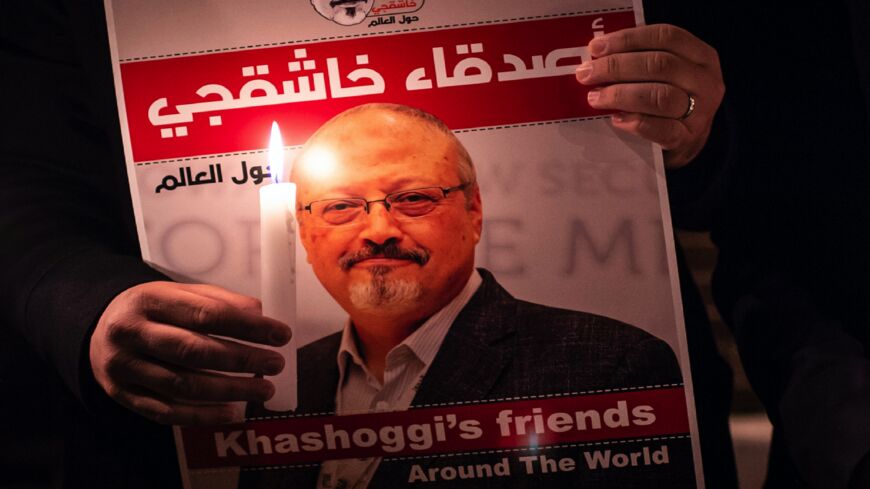A demonstrator holds a poster picturing Saudi journalist Jamal Khashoggi and a lit candle during a gathering outside the Saudi Arabia consulate in Istanbul, on Oct. 25, 2018. 