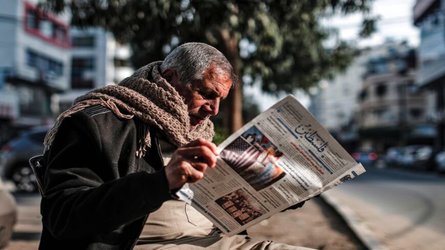 A Palestinian reads the "Filastin" (Palestine) daily newspaper while sitting along a street in Gaza City on Jan. 28, 2020. 