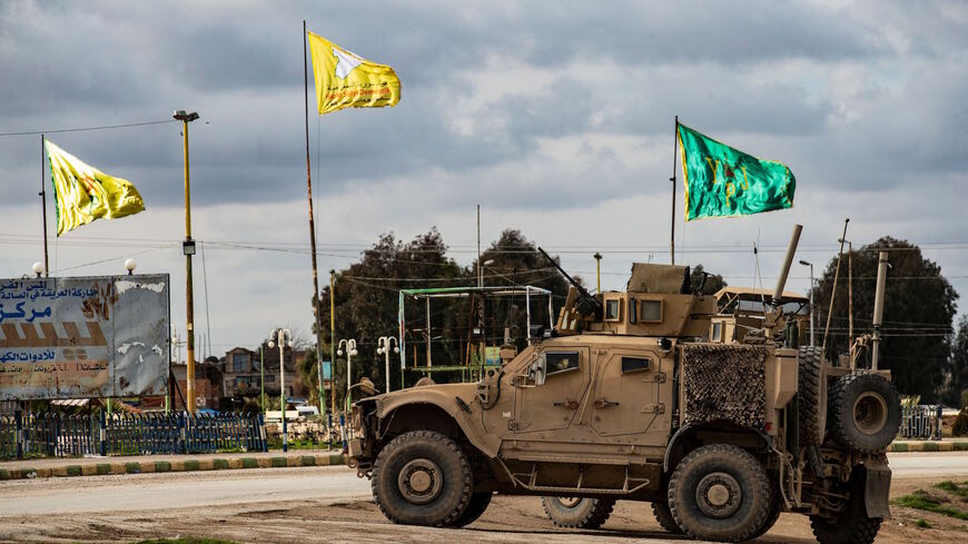A patrol of US military vehicles is seen near the flying yellow flags of the Syrian Democratic Forces (SDF) and green flags of its constituent Women's Protection Forces (YPJ) in the town of Tal Tamr in the northeastern Syrian Hasakeh province along the border with Turkey on Feb. 8, 2020. 