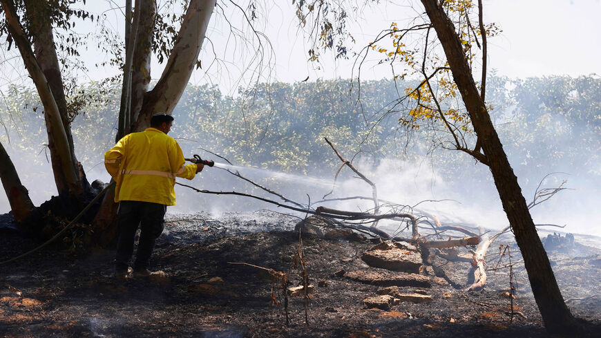 A worker with the Israel Nature and Parks Authority extinguishes a fire in a field near Kibutz Alumim that was reportedly caused by an incendiary balloon launched from the Gaza Strip, Aug. 24, 2020. 