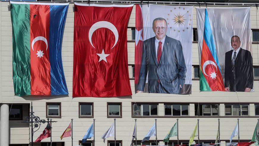The national flags of Azerbaijan (L) and Turkey, and portraits of Turkish President Recep Tayyip Erdogan and Azerbaijani President Ilham Aliyev (R) hang side-by-side on the mayoral building in the Kecioren district of Ankara on October 21, 2020.  