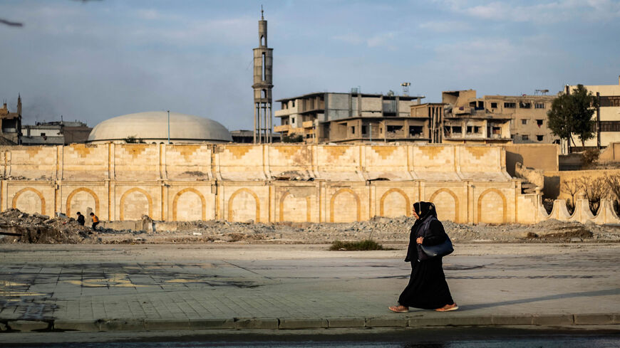 A woman walks in the northern city of Raqqa, the former Syrian capital of the Islamic State, Syria, Dec. 20, 2020.