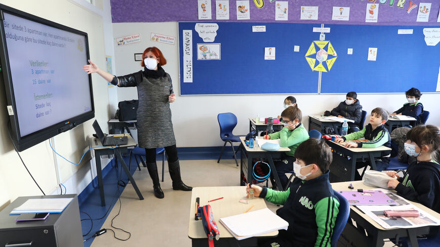 Pupils wearing protective facemasks listen to a teacher in a classroom of a school in Ankara on March 2, 2021, after the country lifted restrictions measures against the Covid-19 pandemic in regions with lower infection rates. 