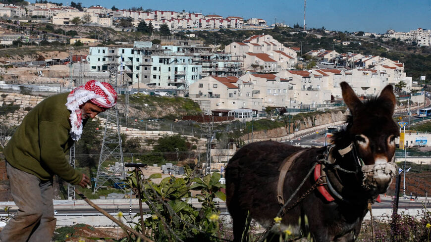 Palestinian farmer Atta Jaber aided by his donkey ploughs his land facing the Israeli settlement of Kiryat Arba, Hebron, West Bank, April 4, 2021.