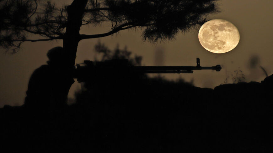 April's Pink Super Moon rises behind a fighter of the Turkish-backed Free Syrian Army in the rebel-held countryside of Idlib province, Syria, April 28, 2021.