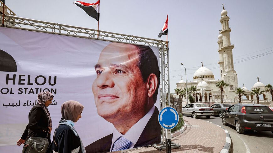 Women walk past a giant banner depicting Egypt's President Abdel Fattah al-Sisi amidst preparations to receive a visiting Egyptian intelligence delegation in Gaza City on May 31, 2021. 