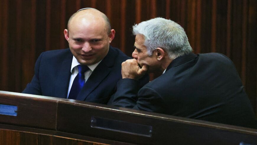 Israel's Yamina party leader, Naftali Bennett (L), smiles as he speaks to Yesh Atid party leader, Yair Lapid, during a special session of the Knesset, Israel's parliament, to elect a new president, in Jerusalem on June 2, 2021.