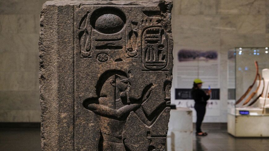 A visitor uses her phone to take a picture of artifacts near a relief dating to the reign of the ancient Egyptian 20th dynasty Pharaoh Ramases III (1184-1053 BC), on display at the new National Museum of Egyptian Civilization (NMEC) in the district of Fustat of Egypt's capital, Cairo, on May 26, 2021.