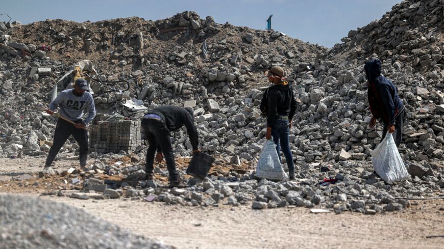 Workmen break rubble into pieces as they recycle salvaged construction materials from buildings destroyed during the May 2021 conflict between Hamas and Israel, at a rubble collection area in Gaza City's eastern suburb of Shujaiya on June 5, 2021.