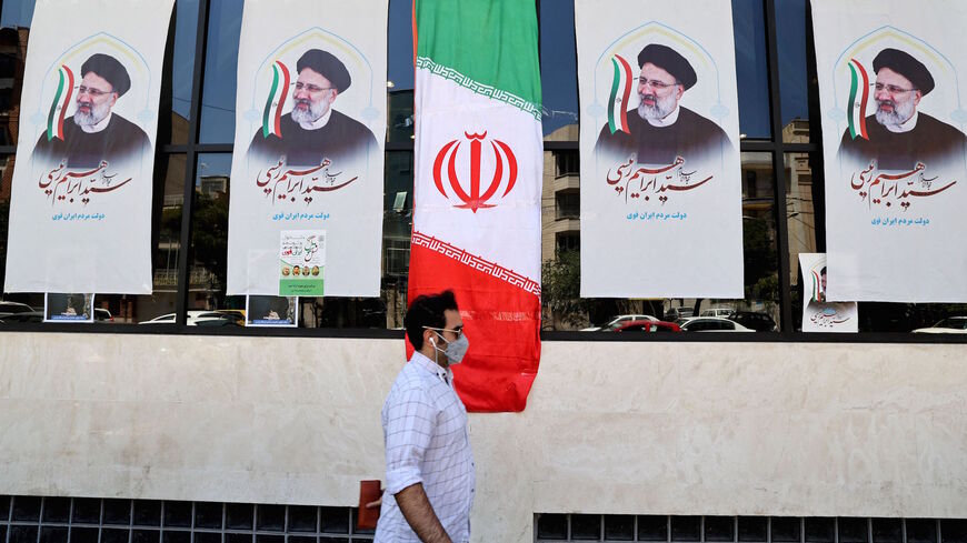 An Iranian man walks by posters of presidential candidate Ebrahim Raisi outside a campaign office in Tehran on June 7, 2021. 