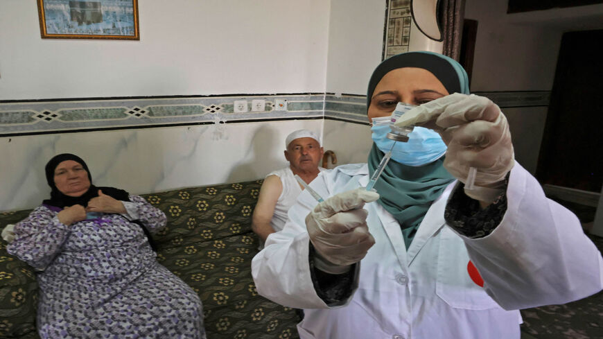A Palestinian member of a Health Ministry mobile unit vaccinates elderly Palestinians against the coronavirus, in the village of Dura near Hebron, West Bank, June 9, 2021.