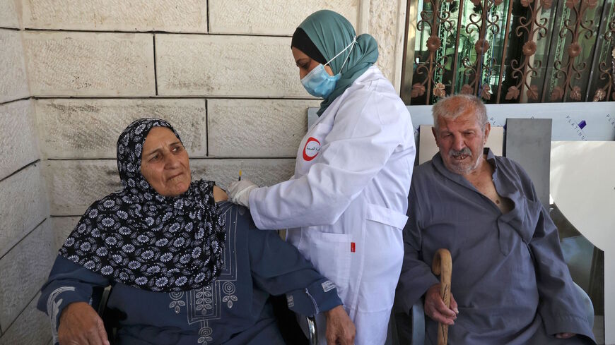 A Palestinian member of a health ministry mobile unit vaccinates elderly Palestinians against the COVID-19 coronavirus, in the village of Dura near Hebron in the occupied West Bank, on June 9, 2021. 