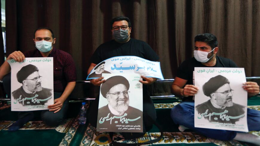 Supporters of Iranian presidential candidate Ebrahim Raisi hold posters of him during an election campaign rally in the capital, Tehran, on June 10, 2021. 