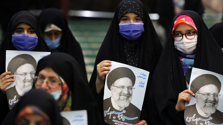 Supporters of Iranian presidential candidate Ebrahim Raisi hold posters of him during an election campaign rally in the capital Tehran, on June 10, 2021.