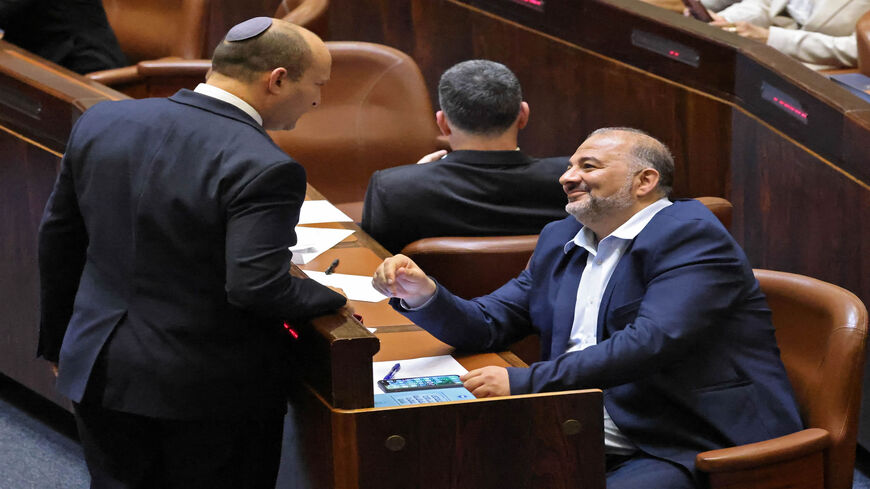 Head of Israel's right-wing Yamina party Naftali Bennett (L) chats with Mansour Abbas, head of the conservative Islamic Raam party, during a special session to vote on a new government at the Knesset, Jerusalem, June 13, 2021.
