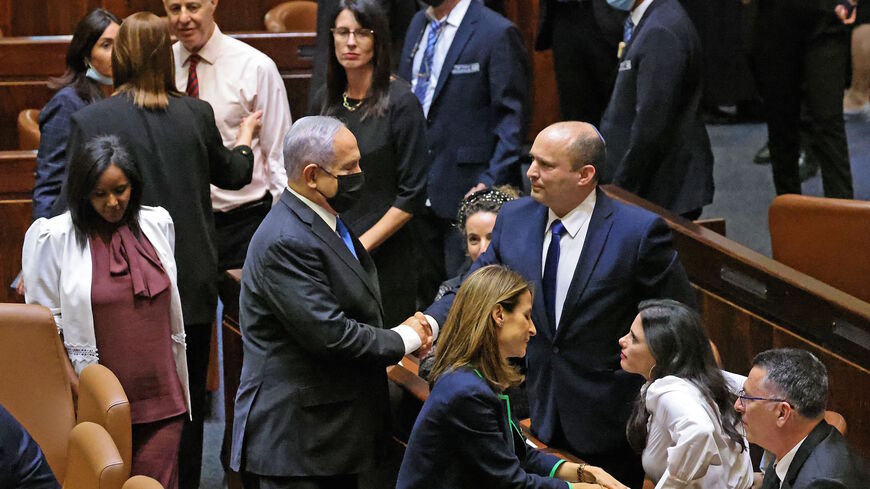 (L to R) Israel's outgoing prime minister Benjamin Netanyahu shakes hands with his successor, incoming Prime Minister Naftali Bennett, after a special session to vote on a new government at the Knesset in Jerusalem, on June 13, 2021. 