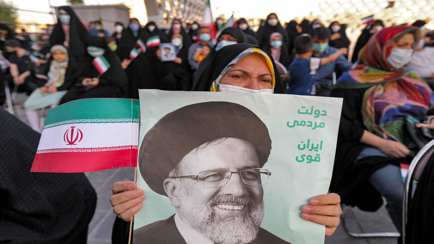 A woman holds a poster of newly elected President Ebrahim Raisi, with text in Persian reading "Government of the people, strong Iran," as supporters celebrate his victory in Imam Hussein Square, Tehran, Iran, June 19, 2021.