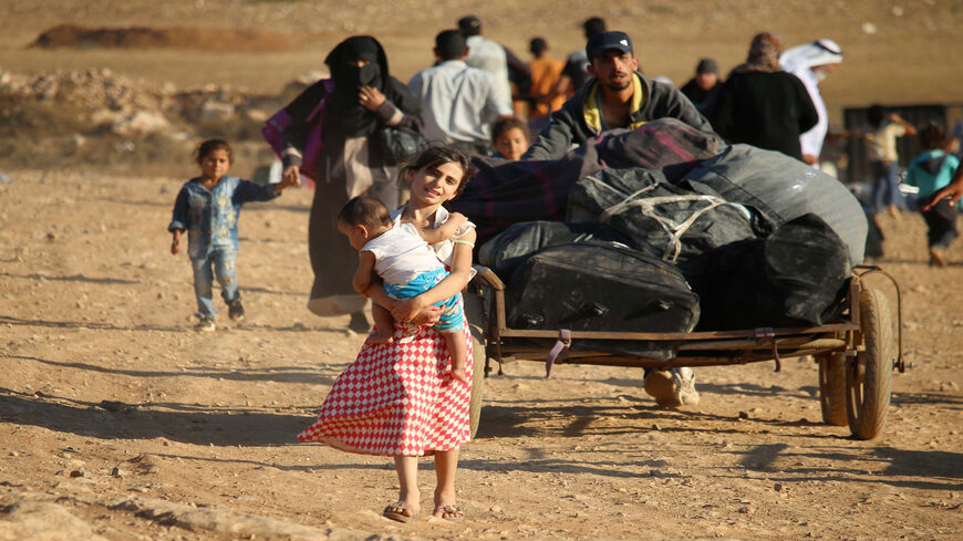 Syrian refugees carry belongings as they return to Syria after crossing the Jordanian border near the town of Nasib, in the southern province of Daraa, Aug. 29, 2017.