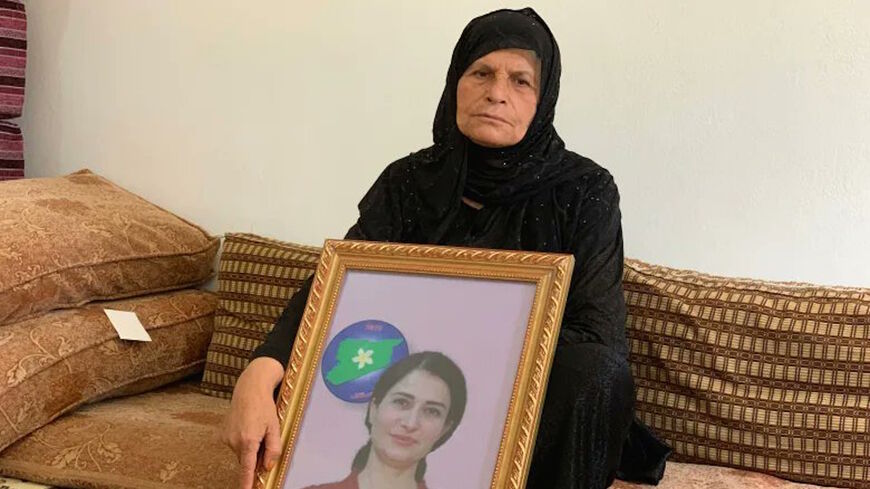 Hevrin Khalaf's mother, Souad Mohammad, is seen with an image of her daughter in this undated photo.