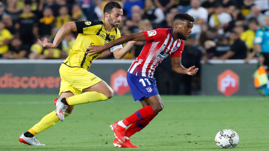 Atletico Madrid's French midfielder Thomas Lemar (R) is marked by Beitar's midfielder Dan Einbinder during the friendly soccer match between Beitar Jerusalem and Atletico Madrid at Teddy Stadium, Jerusalem, May 21, 2019.