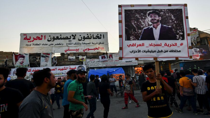 An Iraqi demonstrator carries a portrait of an activist who has been missing for weeks and was allegedly kidnapped