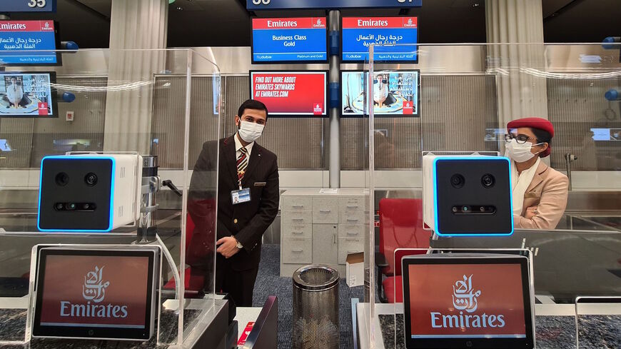 Emirates airlines employees behind check in counters equipped with a fast-track identification system that uses face and iris-recognition technologies, at Dubai international airport, on March 7, 2021.