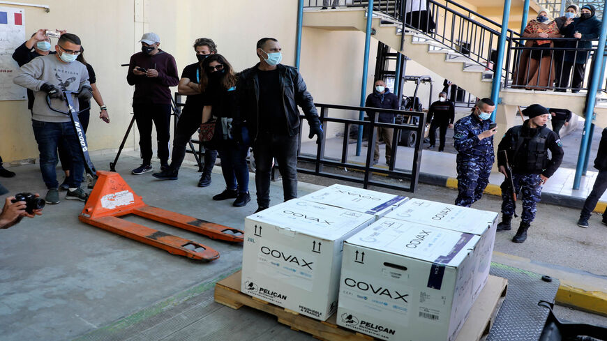 A worker unloads a refrigerated truck carrying the first delivery of the coronavirus vaccine via the United Nations Covax program, to be kept at the Palestinian Authority's storage facility in Nablus, West Bank, March 17, 2021.