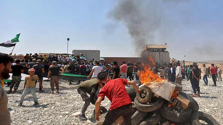 Syrians burn tyres as they protest in front of a Turkish military outpost during a demonstration against Turkey's perceived inaction over the latest Syrian regime attacks, in the town of Maataram near Ariha in the rebel-held northwestern Idlib province, Syria, July 23, 2021.