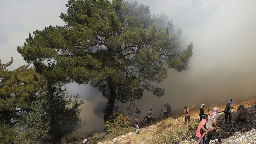 Volunteers help to extinguish a forest fire in the Qubayyat area of northern Lebanon's remote Akkar region on July 29, 2021. 