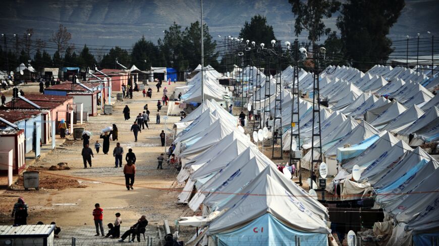 Syrian refugees walk among tents at Karkamis' refugee camp on January 16, 2014, near the town of Gaziantep, south of Turkey.