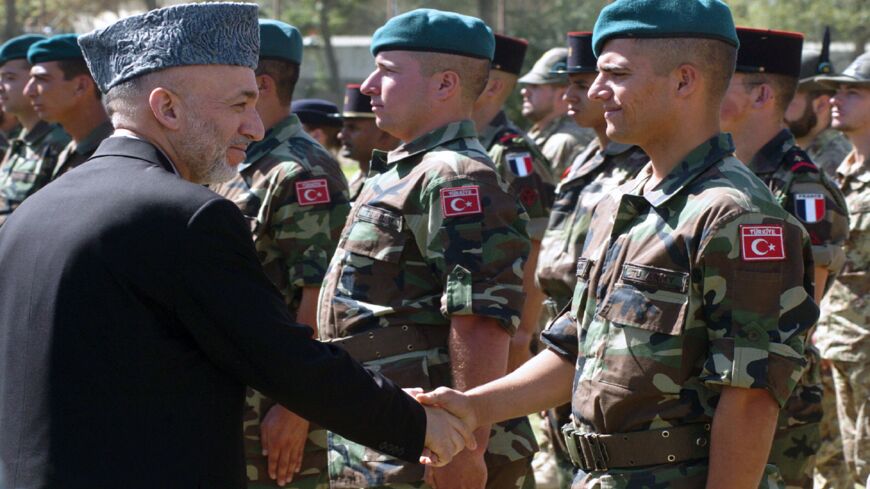 Afghan President Hamid Karzai (L) shakes hands with a Turkish soldier.