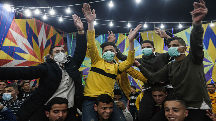 Palestinian men, some wearing face masks, dance at a wedding a day before authorities impose a ban on festive events as a protective measure against the coronavirus  pandemic, Rafah, Gaza Strip, March 21, 2020.