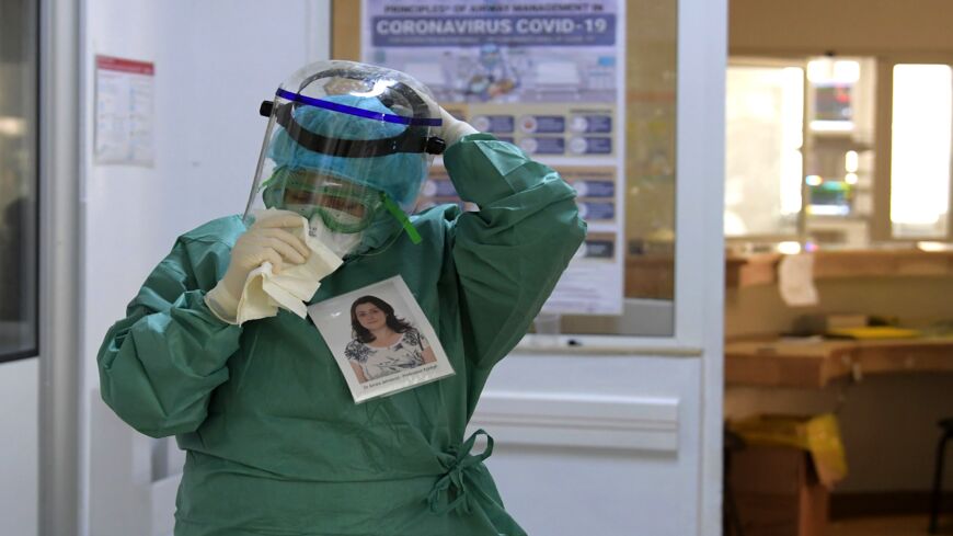 Amira Jamoussi, with a picture of herself pinned on her protective outfit to help others recognize her, gets ready to see patients at the Abderrahmane Memmi Hospital.