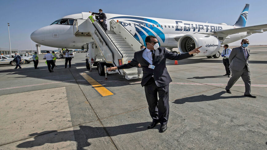 Egyptian officials wearing face masks against the coronavirus are pictured near an EgyptAir Airbus A320 neo aircraft at Hurghada Airport, Egypt, June 18, 2020.