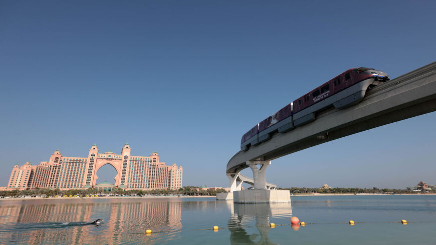 A man swims near a section of the Palm Jumeirah monorail, with the Atlantis Hotel in the background, Dubai, United Arab Emirates, Nov. 16, 2020.