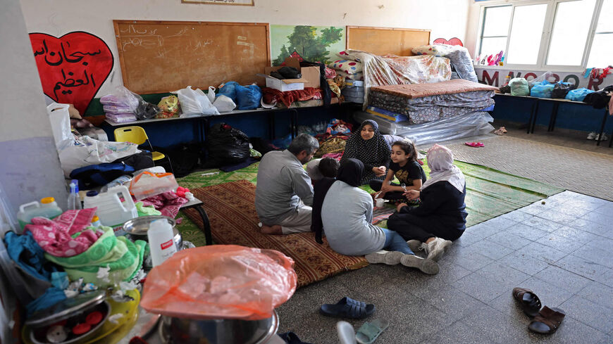 Palestinian Mansour Abu Ghadyan and members of his family share a meal inside a classroom of an UNRWA-run school where they will be living temporarily after their home was damaged during the recent Israeli bombing in Gaza City, Gaza Strip, May 29, 2021.