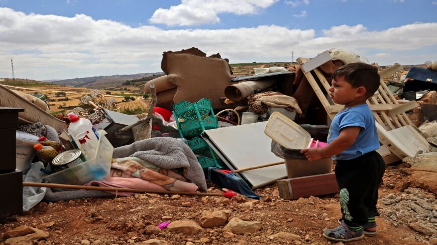 A child looks on as a Palestinian family checks their belongings after Israeli machinery demolished their house located within Area C of the occupied West Bank.