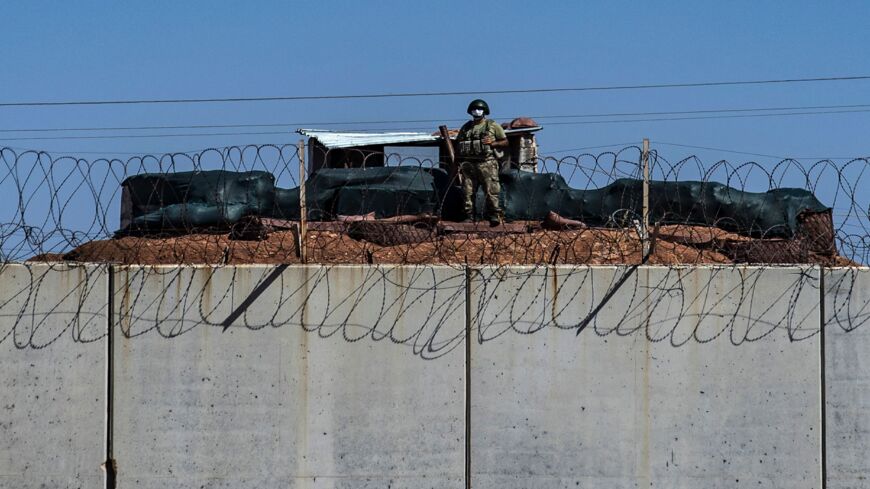 A Turkish soldier stands behind the border with Syria.