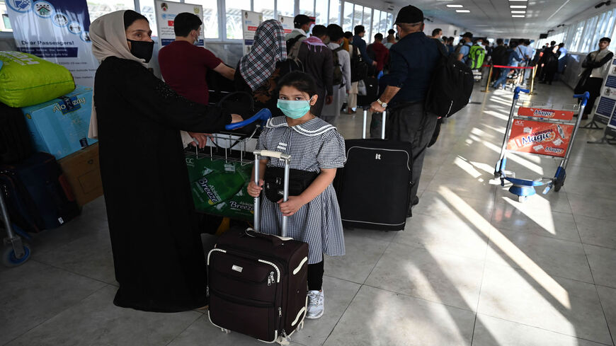 The family (front) of an Afghan national working at the French Embassy queue at Hamid Karzai International Airport as they prepare to leave on a special flight to France, Kabul, Afghanistan, July 17, 2021.