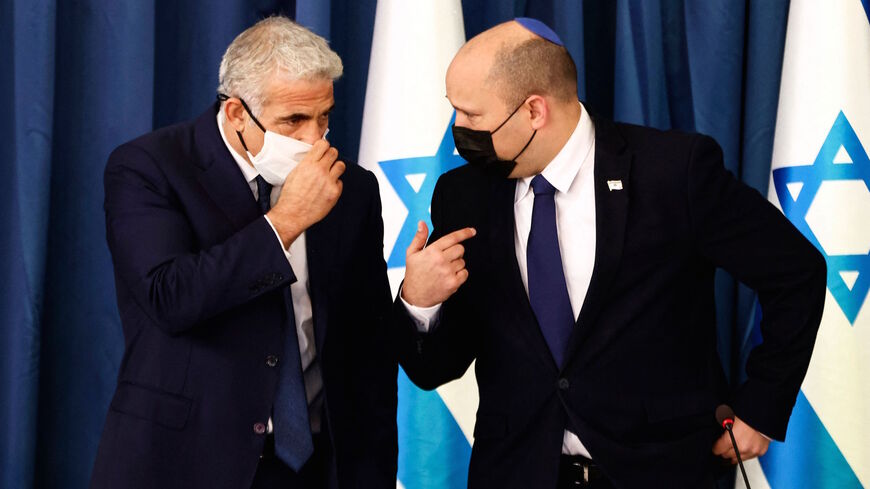 Israeli Prime Minister Naftali Bennett (R) speaks to Foreign Minister Yair Lapid, at the weekly cabinet meeting in Jerusalem on Aug. 8, 2021. 
