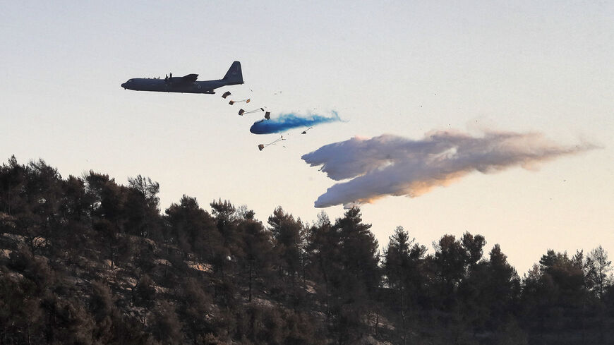 A Lockheed C-130 Hercules aircraft releases fire retardant while attempting to extinguish a forest fire near Kibbutz Tzova, west of Jerusalem, central Israel, Aug. 17, 2021.