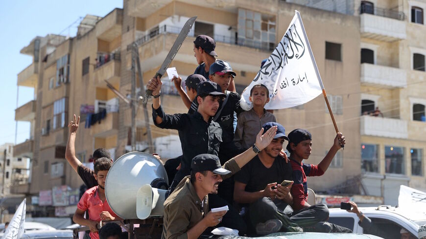 Members of Syria's top jihadist group the Hayat Tahrir al-Sham (HTS) alliance, led by al-Qaeda's former Syria affiliate, parade with their flags and those of the Taliban's declared "Islamic Emirate of Afghanistan" through the rebel-held northwestern city of Idlib on Aug. 20, 2021.