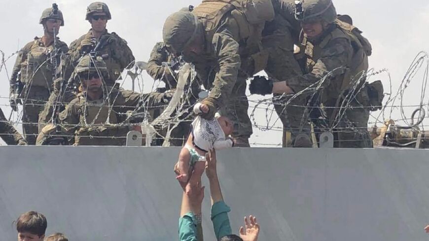 Marine grabs baby handed over wall at Kabul airport 