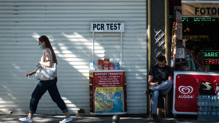 A woman walks past a tourist shop promoting PCR tests during a three week nationwide coronavirus lockdown on May 5, 2021 in Istanbul, Turkey. 