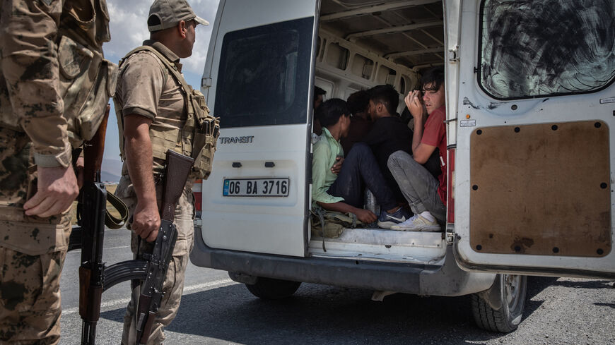 Jandarma officers monitor Afghan migrants sitting in the back of a smuggler's van that was caught transporting the migrants from the Turkey-Iran border on July 10, 2021 in Caldiran, Turkey.