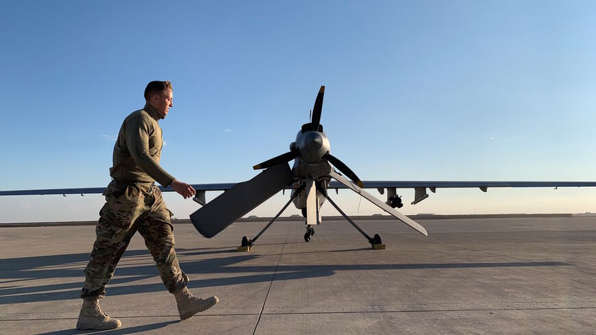 A picture taken on January 13, 2020, during a press tour organised by the US-led coalition fighting the remnants of the Islamic State group, shows a member the US forces walking past a drone in the Ain al-Asad airbase in the western Iraqi province of Anbar. 